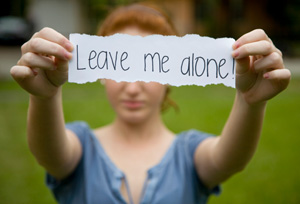 Teen holding a sign that reads - Leave me alone.