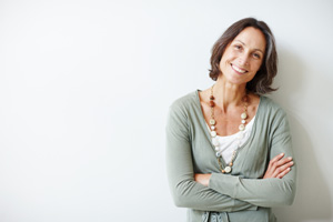 Elegant middle aged woman with her arms crossed against white.