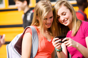 Two females reviewing text messages on a handheld device.